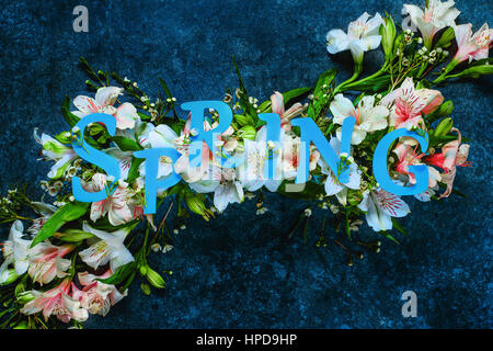 La molla di scritte con il bianco e rosa fiori su un marmo scuro dello sfondo. Le lettere vengono effettuate dal pastello carta. Foto Stock