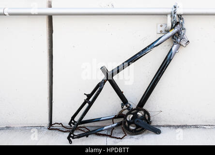 Concatenamento di una bicicletta non ha impedito che i ladri dal furto di parti come ruote da esso. Foto Stock