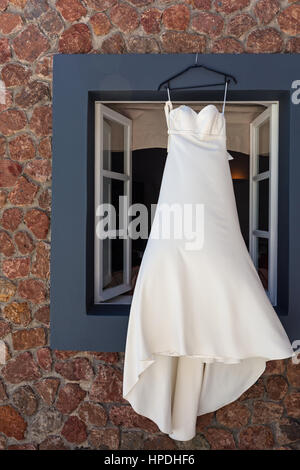 White abito da sposa appeso al di fuori della finestra Foto Stock