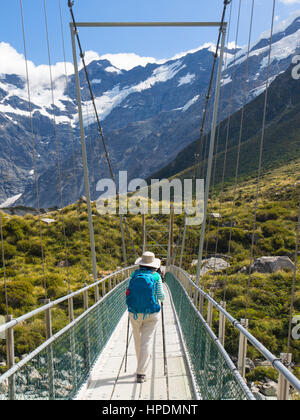 Dal Parco Nazionale Aoraki/Mount Cook, Canterbury, Nuova Zelanda. Escursionista sull'Hooker Valley Via attraversando la sospensione ponte sopra il fiume Hooker. Foto Stock