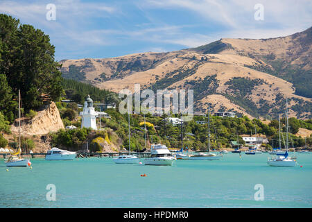 Akaroa, Canterbury, Nuova Zelanda. Vista attraverso le acque turchesi di Akaroa Harbour, faro storico prominente. Foto Stock