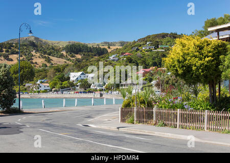 Akaroa, Canterbury, Nuova Zelanda. Vista lungo la strada della spiaggia di porto di Akaroa. Foto Stock