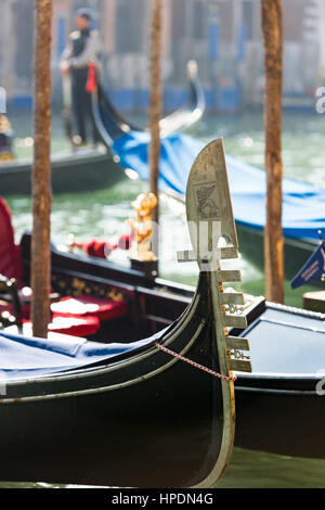 un gondoliere è visto in piedi in una silhouette sfocata con l'iconica gonna in gondola mostrata in dettaglio in primo piano Foto Stock