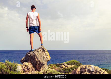 Happy trail runner, conquista il successo in esecuzione o escursionismo Realizzazione concetto aziendale con l'uomo celebrando e guardando l'oceano. Foto Stock