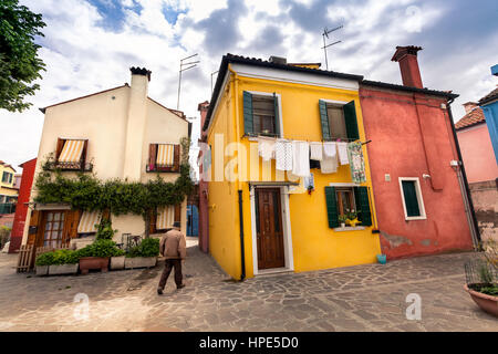 Isola di Burano, Venezia, Italia: 26 aprile 2016. Colorfully case dipinte e il vecchio uomo a piedi. Foto Stock