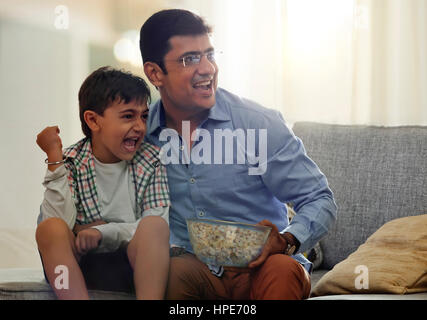 Padre e figlio di guardare la televisione e mangiare popcorn Foto Stock