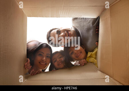 Famiglia guardando in giù a telecamera attraverso la scatola di cartone Foto Stock