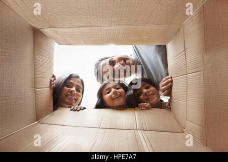 Famiglia guardando in giù a telecamera attraverso la scatola di cartone Foto Stock