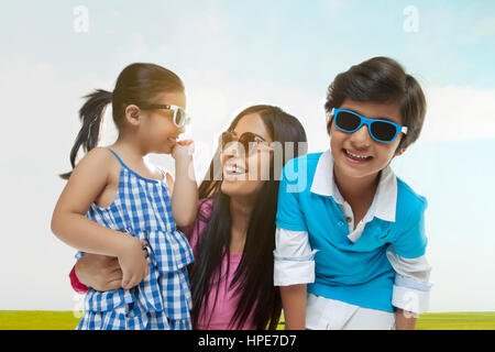 Famiglia sorridente indossando occhiali da sole divertimento in un parco sulla giornata di sole Foto Stock