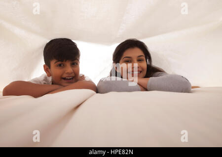 Sorridente madre e figlio al divertimento in camera da letto Foto Stock