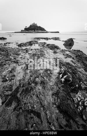 In bianco e nero alba shot su foschia mattutina con una lunga esposizione di St Michael's Mount, West Cornwall, Inghilterra, Regno Unito nel mese di febbraio Foto Stock
