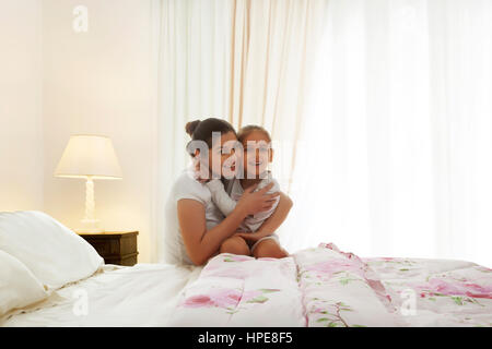 Ritratto di Madre e figlia abbracciando in camera da letto Foto Stock