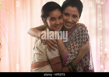 Sorridente figlia adolescente in sari abbracciando la madre Foto Stock