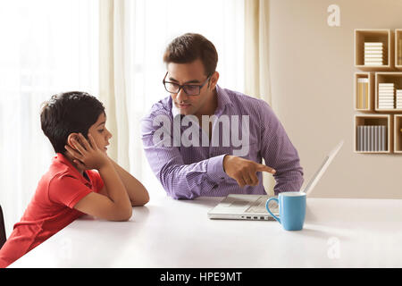 Insegnamento di padre in figlio utilizzando portatile a casa Foto Stock