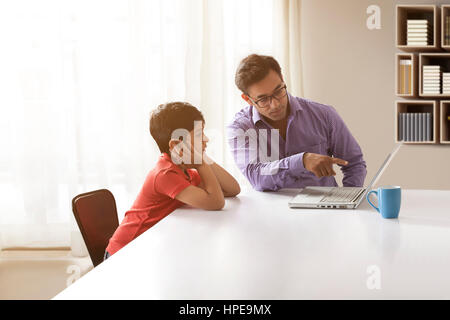 Insegnamento di padre in figlio utilizzando portatile a casa Foto Stock
