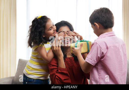 Due bambini presentando dono alla loro madre Foto Stock