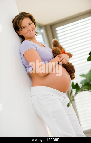Modello rilasciato , Schwangere Frau mit Teddybaer in der mano - donna incinta con Teddy bear Foto Stock
