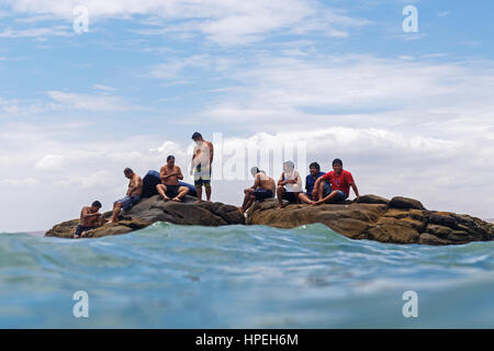 Gli uomini seduti su una roccia isola nell'oceano Foto Stock