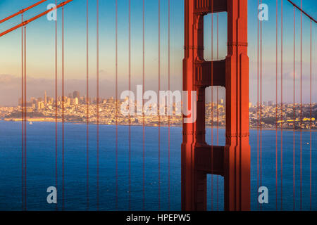 Visualizzazione classica del famoso Golden Gate Bridge con lo skyline di San Francisco in sfondo illuminato nel bellissimo golden luce della sera al tramonto Foto Stock