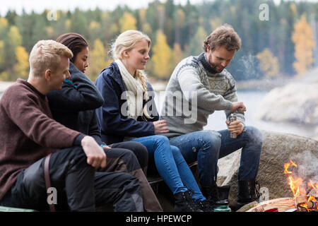 Multietnica amici guardando l'uomo macinazione di caffè al campeggio Foto Stock