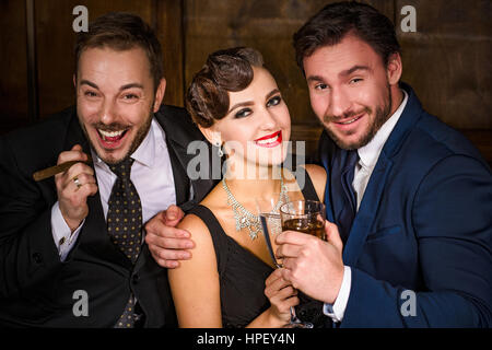 Ricchezza, ricchezza, concetti di lusso. Migliore happy amici di partito nel lussuoso ristorante. La gente di distensione e di riposo con alcol e sigari. Foto Stock