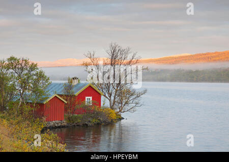 Tipica rorbu rosso / rorbuer o Fisherman's cabin lungo il lago Avsjoen / Avsjøen in autunno a Dovrefjell, Oppland, Norvegia e Scandinavia Foto Stock
