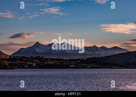 Cuillin Hills Mountain Range, sul Loch Portree, sull'Isola di Skye in Scozia, contro un drammatico cielo di nuvole, riflettendo l'impostazione sun. Foto Stock