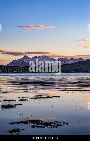 Cuillin Hills Mountain Range, sul Loch Portree, sull'Isola di Skye in Scozia, contro un drammatico cielo di nuvole, riflettendo l'impostazione sun. Foto Stock