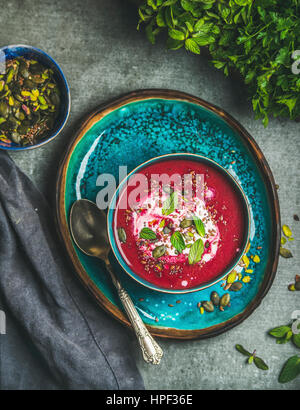 Primavera detox zuppa di barbabietole con la menta, chia, lino e semi di zucca su un blu brillante piastra ceramica su cemento grigio Sfondo, vista dall'alto. Dieta, clea Foto Stock