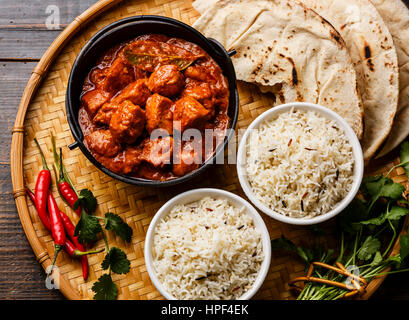 Pollo Tikka masala curry piccante alimenti a base di carne in ghisa pentola con il riso e pane naan close up Foto Stock