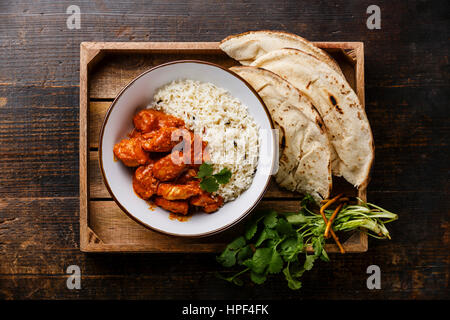 Pollo Tikka masala curry piccante alimenti a base di carne con riso e pane naan nel vassoio su sfondo di legno Foto Stock