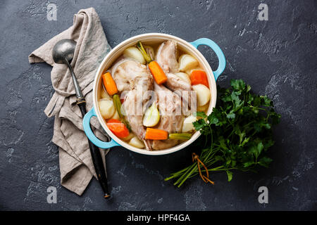 Stufato di coniglio con patate e carote in ghisa sulla pentola pietra scura sullo sfondo Foto Stock