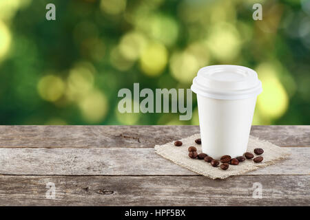 Bicchiere di carta di caffè sul naturale al di fuori di sfondo con copia spazio. Il caffè sul tavolo sulla natura dello sfondo. Il caffè da asporto. Caffè di andare Foto Stock