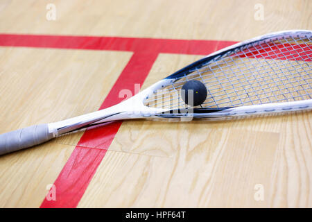 Racchette da squash e la palla sullo sfondo di legno. Raquetball attrezzatura. Squash palla e squash racket sulla corte accanto a una linea rossa. Foto con sele Foto Stock