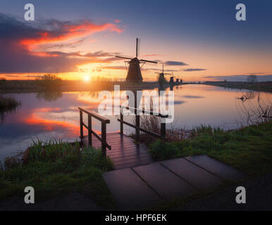 Silhouette di mulini a vento di sunrise in Kinderdijk, Paesi Bassi. Paesaggio agreste con molo in legno contro i mulini a vento olandese nella nebbia vicino i canali Foto Stock