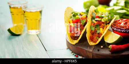 Mexican nachos chips e tacos con carne, fagioli e salsa di sfondo rustico Foto Stock