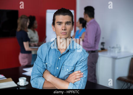 Ritratto di business executive in piedi con le braccia incrociate a riunione in ufficio Foto Stock