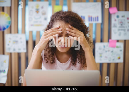 Femmina frustrato graphic designer con la localizzazione del notebook alla scrivania in ufficio Foto Stock
