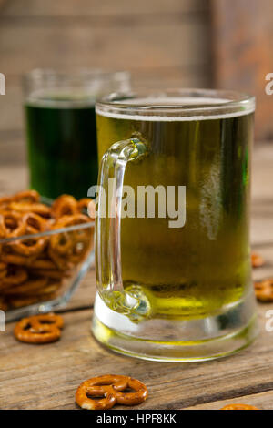 Il giorno di San Patrizio due boccali di birra con pretzel su una superficie di legno Foto Stock