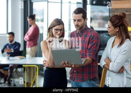 Gli imprenditori aventi la discussione su computer portatile in ufficio Foto Stock