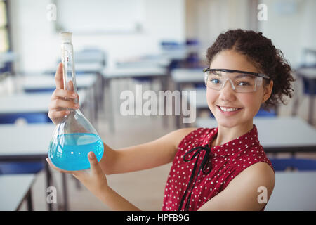Ritratto di sorridere schoolgirl facendo un esperimento di chimica in laboratorio a scuola Foto Stock