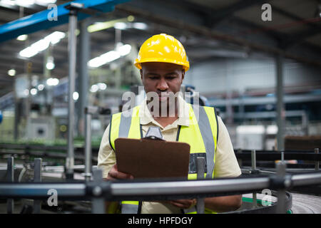 Considerato operaio di fabbrica guardando negli appunti in fabbrica Foto Stock