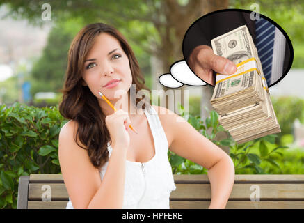 Considerato giovane donna con la mano che tiene la risma di denaro all'interno di bolle di pensiero. Foto Stock