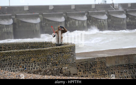 Brighton Regno Unito 22 Febbraio 2017 - un viandante si blocca sul suo cappello forti venti in Brighton Seafront questa mattina come tempesta Doris si dirige verso la Gran Bretagna nei prossimi giorni . Fotografia scattata da Simon Dack Foto Stock