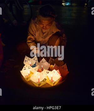 Vecchia donna vendita di candele per la luna piena festival nella città vecchia di Hoi An, Vietnam Foto Stock