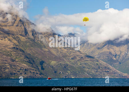 Queenstown, Otago, Nuova Zelanda. Il parasailing sul lago Wakatipu, Walter Peak avvolto nella nube. Foto Stock