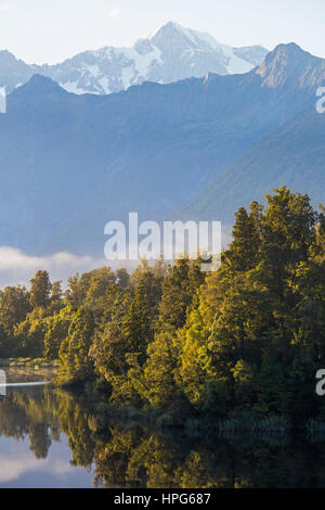 Fox Glacier, Westland Tai Poutini National Park, West Coast, Nuova Zelanda. Vista sul tranquillo Lago Matheson a Aoraki/Mount Cook, alba. Foto Stock