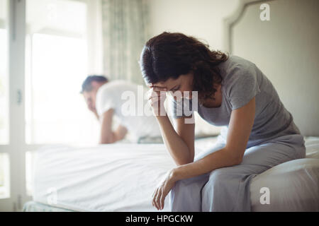 Tesi donna seduta su di un letto in camera da letto Foto Stock