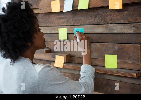 Femmina di graphic designer guardando sticky notes presso il creative office Foto Stock