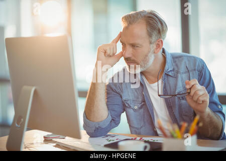 Maschio di graphic designer che lavora sul computer in ufficio Foto Stock